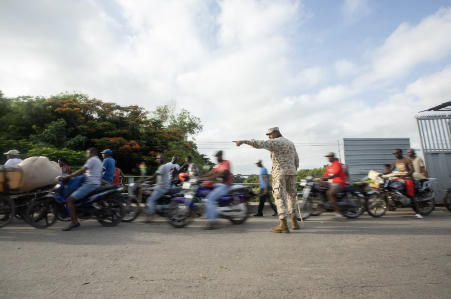 A member of the Dominican Republic's Specialized Border Security Corps directs pedestrians arriving from Haiti at the border bridge between Ouanaminthe, Haiti, and Dajabon, the Dominican Republic, in August. (Bloomberg via Getty Images)