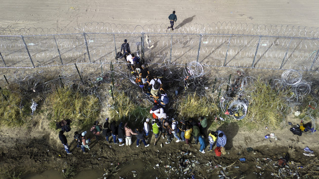 In an aerial view, immigrants pass through coils of razor wire while crossing the U.S.-Mexico border on March 13, 2024, in El Paso, Texas. | John Moore/Getty Images