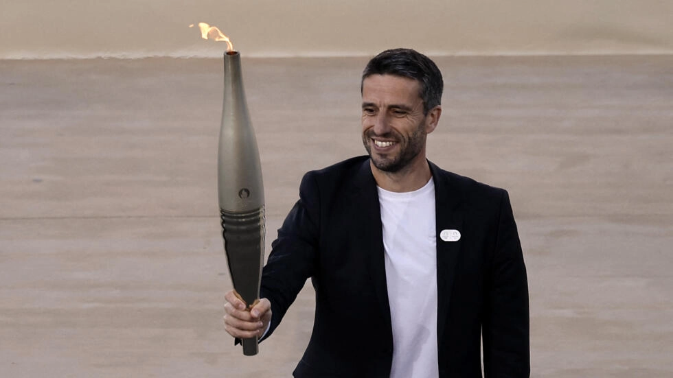 Tony Estanguet, president of the Paris 2024 Olympics organising committee, holds the Olympic flame during the Handover Ceremony on April 26, 2024. © Louisa Gouliamaki, Reuters