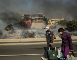 James and Josie Ralstin carry belongings from their Ventura, Calif., home as flames from a wildfire consume another residence on Dec. 5, 2017. The couple evacuated early Tuesday morning as the fire approached, but returned to retrieve medications and
