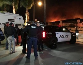 A fire near Santa Paula burns in the background on Dec. 4, 2017, as public safety personnel gather at the command post.